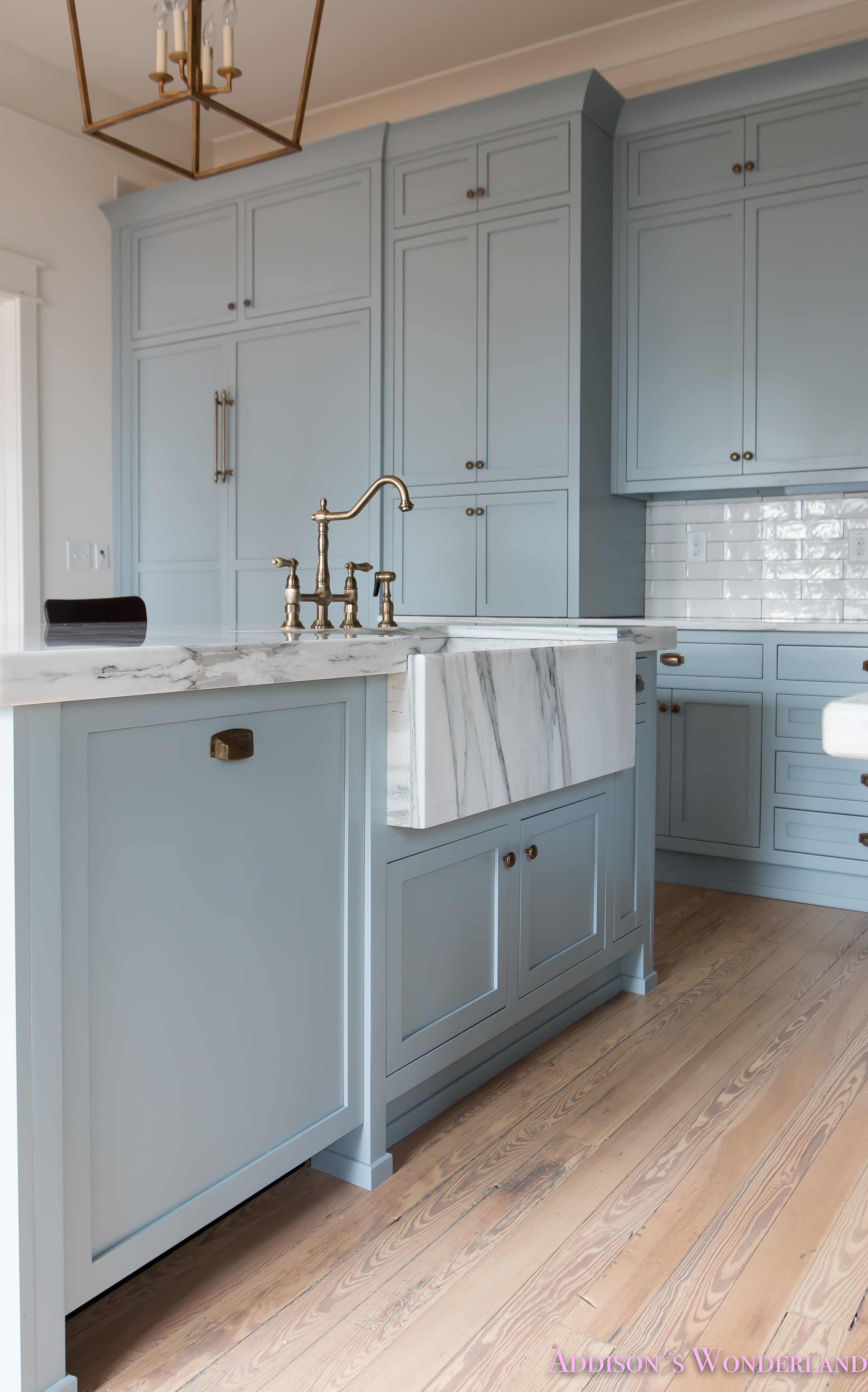 https://addisonswonderland.com/our-vintage-modern-kitchen-reveal/a-classic-vintage-modern-kitchen-blue-gray-cabinets-inset-shaker-black-gold-vent-hood-antique-brass-faucet-white-subway-backsplash-tile-gold-open-shelves-13-of-16/