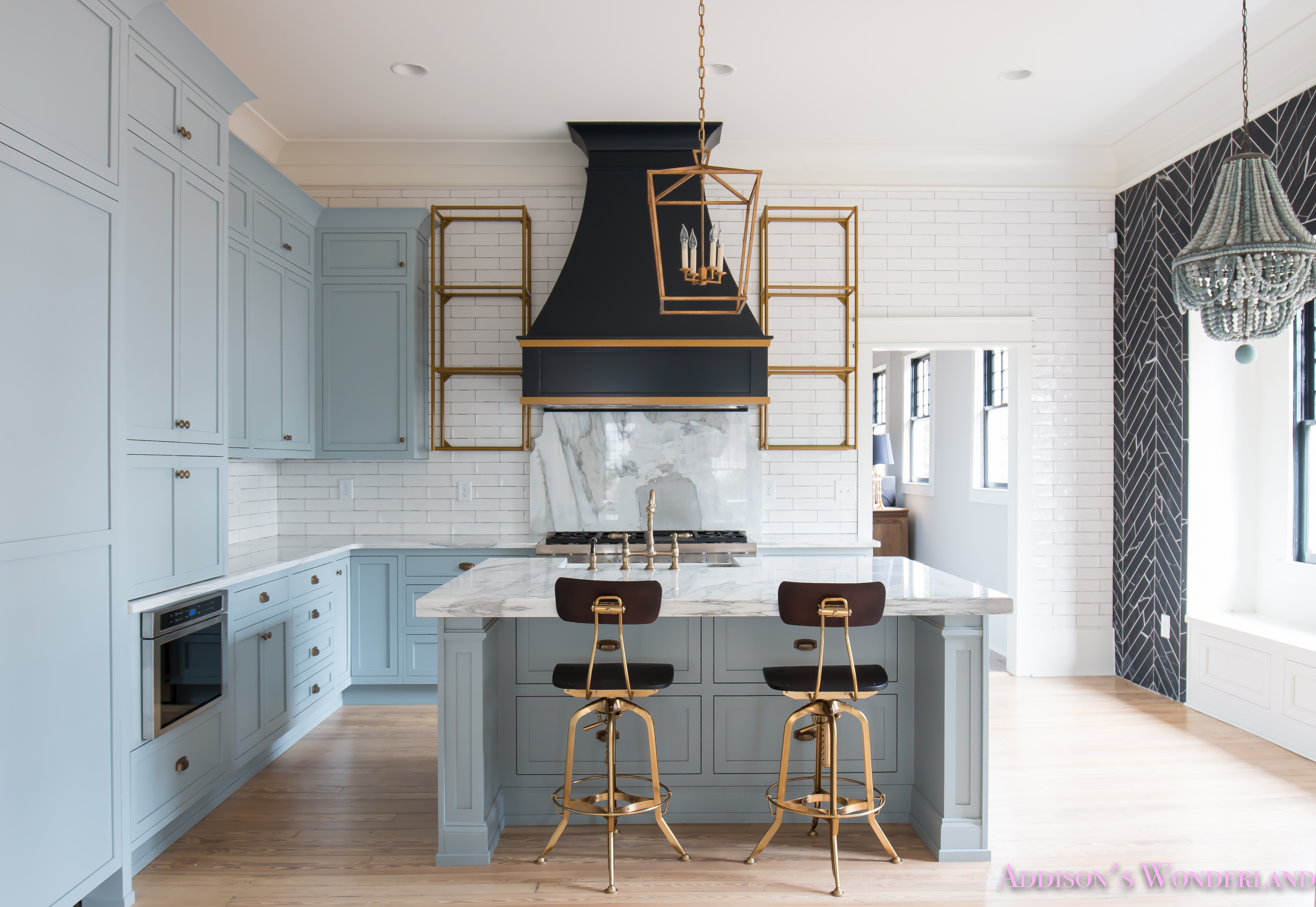 https://addisonswonderland.com/our-vintage-modern-kitchen-reveal/a-classic-vintage-modern-kitchen-blue-gray-cabinets-inset-shaker-black-gold-vent-hood-antique-brass-faucet-white-subway-backsplash-tile-gold-open-shelves-6-of-16/
